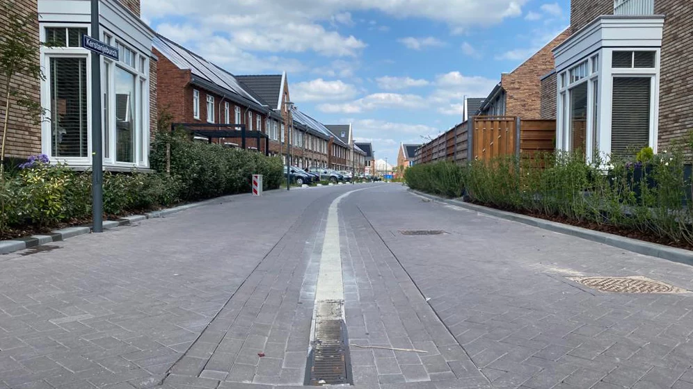 Een straatbeeld met een stoep en in het midden een watergoot voor het opvangen van hemelwater.